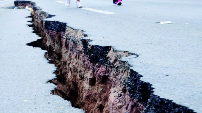People walk along a cracked road in Iquique, northern Chile, on April 2, 2014 a day after a powerful 8.2-magnitude earthquake hit off Chile's Pacific coast. An 8.2-magnitude earthquake hit Chile late Tuesday, killing at least six people and generating tsunami waves that might ripple as far as Indonesia. AFP PHOTO / ALDO SOLIMANO        (Photo credit should read Aldo Solimano/AFP/Getty Images)